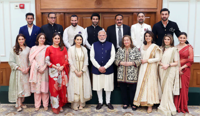 A group of elegantly dressed individuals posing with a prominent figure indoors