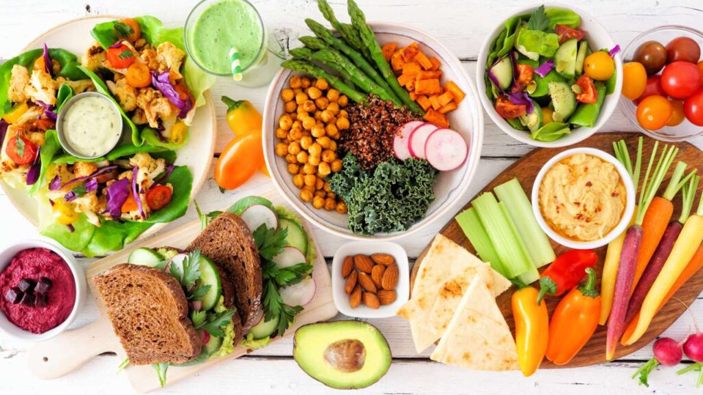 8 Tips for Keeping a Youthful Look 2 A colorful assortment of healthy dishes including lettuce wraps, quinoa, various vegetables, hummus, and smoothies showcasing a nutritious, plant-based feast.