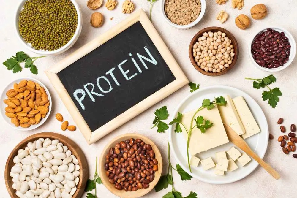 15 Research-backed methods for losing weight without exercise 2 An assortment of plant-based proteins including legumes, nuts, and tofu arranged around a chalkboard displaying the word "PROTEIN."