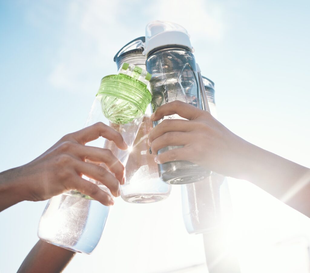 15 Research-backed methods for losing weight without exercise 4 Hands clinking various water bottles against a bright sky, symbolizing celebration and healthy hydration.