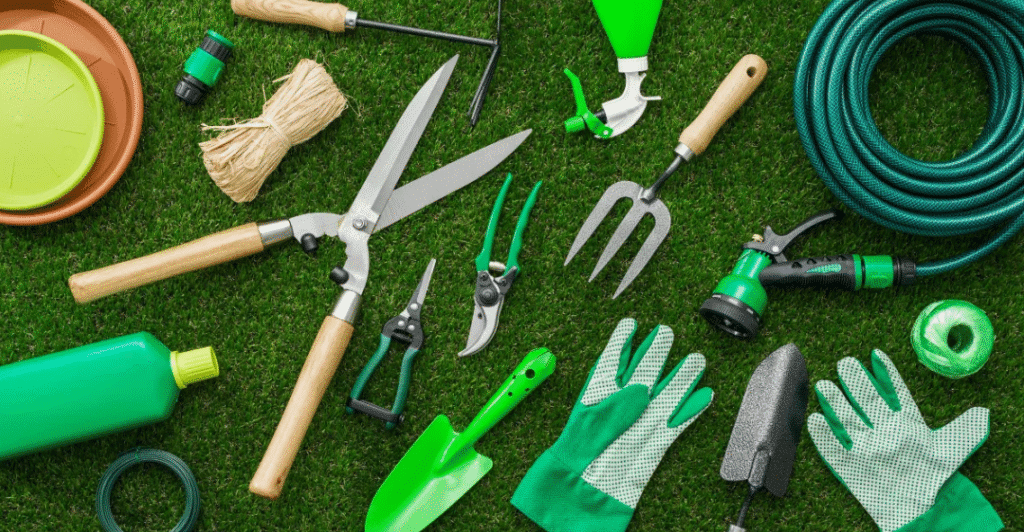 Tips for Beginner Gardeners in India 3 A collection of green gardening tools laid out on artificial grass, including scissors, gloves, a watering hose, trowels, and various gardening implements.