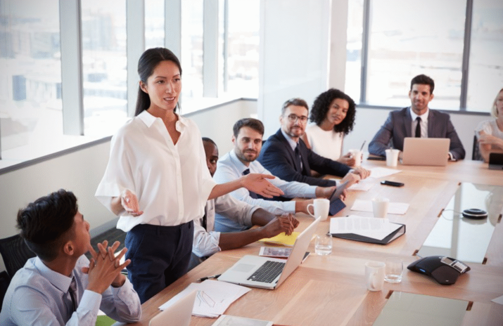 10 Habits of Successful People You Can Begin Practicing Today 3 A professional woman leads a discussion in a modern conference room with a diverse group of attendees listening attentively.