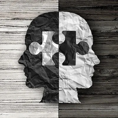 Struggling with Overthinking? 2 An artistic depiction of two silhouette profiles divided by a puzzle piece, blending black and white textures on a wooden background.