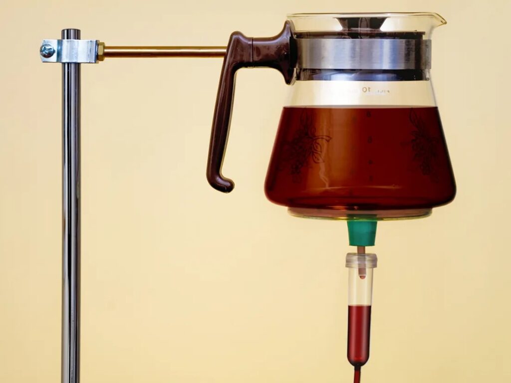 15 Research-backed methods for losing weight without exercise 5 A glass carafe filled with dark liquid on a stand, connected to a tube with a drop of red liquid, set against a pale background.