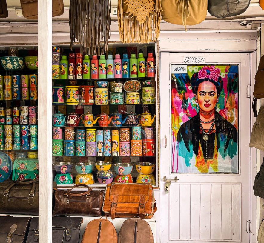 Hippie Trails in India That Promise a Journey to Freedom 4 Colorful decorative items and bags displayed in a shop, featuring a prominent Frida Kahlo portrait on the door.
