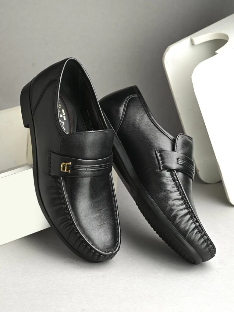 Things We Shouldn't Gift To Anybody 2 A pair of elegant black leather slip-on shoes featuring a stitched design and decorative band, set against a neutral background.