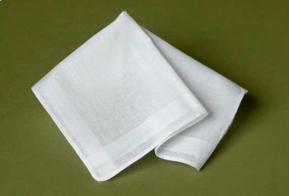 Things We Shouldn't Gift To Anybody 5 A neatly folded white linen handkerchief positioned on a green background.