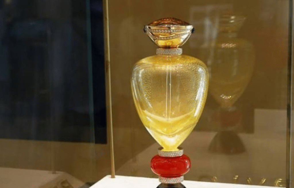 Things We Shouldn't Gift To Anybody 6 A beautifully crafted perfume bottle with a golden hue, adorned with intricate details and set in a glass display.