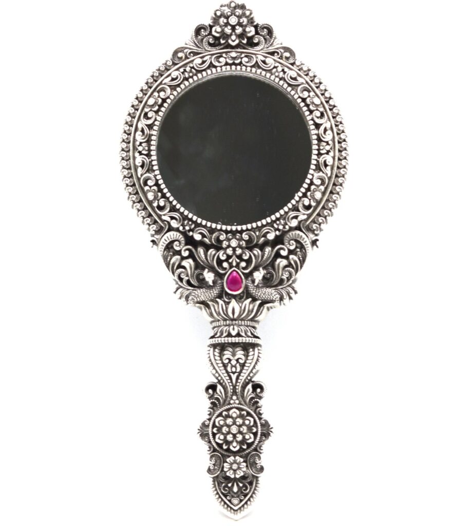 Things We Shouldn't Gift To Anybody 4 : An intricately designed silver hand mirror featuring floral patterns and a central pink gemstone.