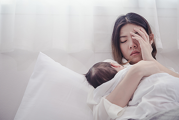 Why Half Of The Couples In Midlife Are In A Sexless Marriage 3 A mother gently holds her newborn baby while resting in a serene, softly lit setting.