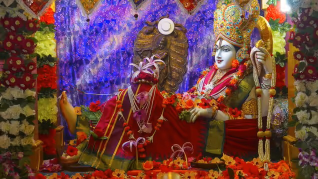 A beautifully adorned idol of Lord Rama surrounded by vibrant flowers and colorful decorations in a serene temple setting.