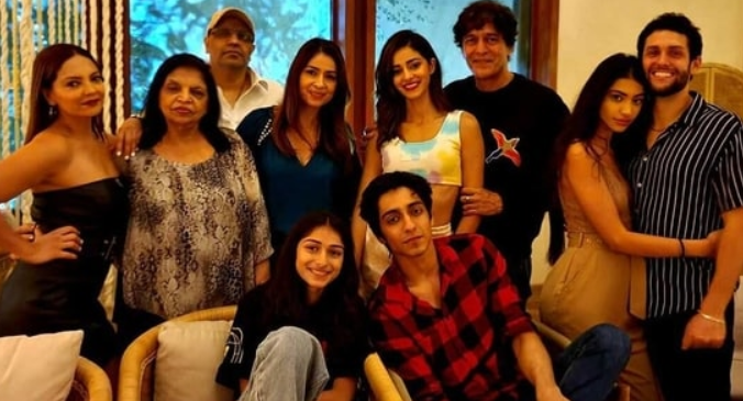 A diverse group of people posing together in a cozy indoor setting, smiling and enjoying a family gathering.