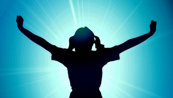A silhouetted figure with outstretched arms against a radiant blue background, symbolizing freedom and happiness.