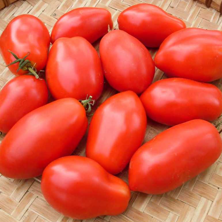 A cluster of vibrant red Roma tomatoes arranged on a woven surface.