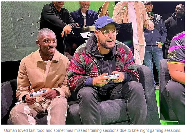 Two men enjoying a gaming session on a couch at an event, with others in the background celebrating and having fun.